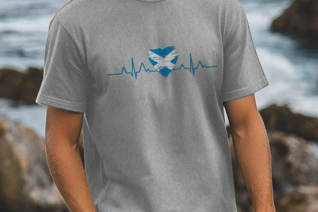 Man wearing a gray t-shirt with a blue and white design by the ocean.