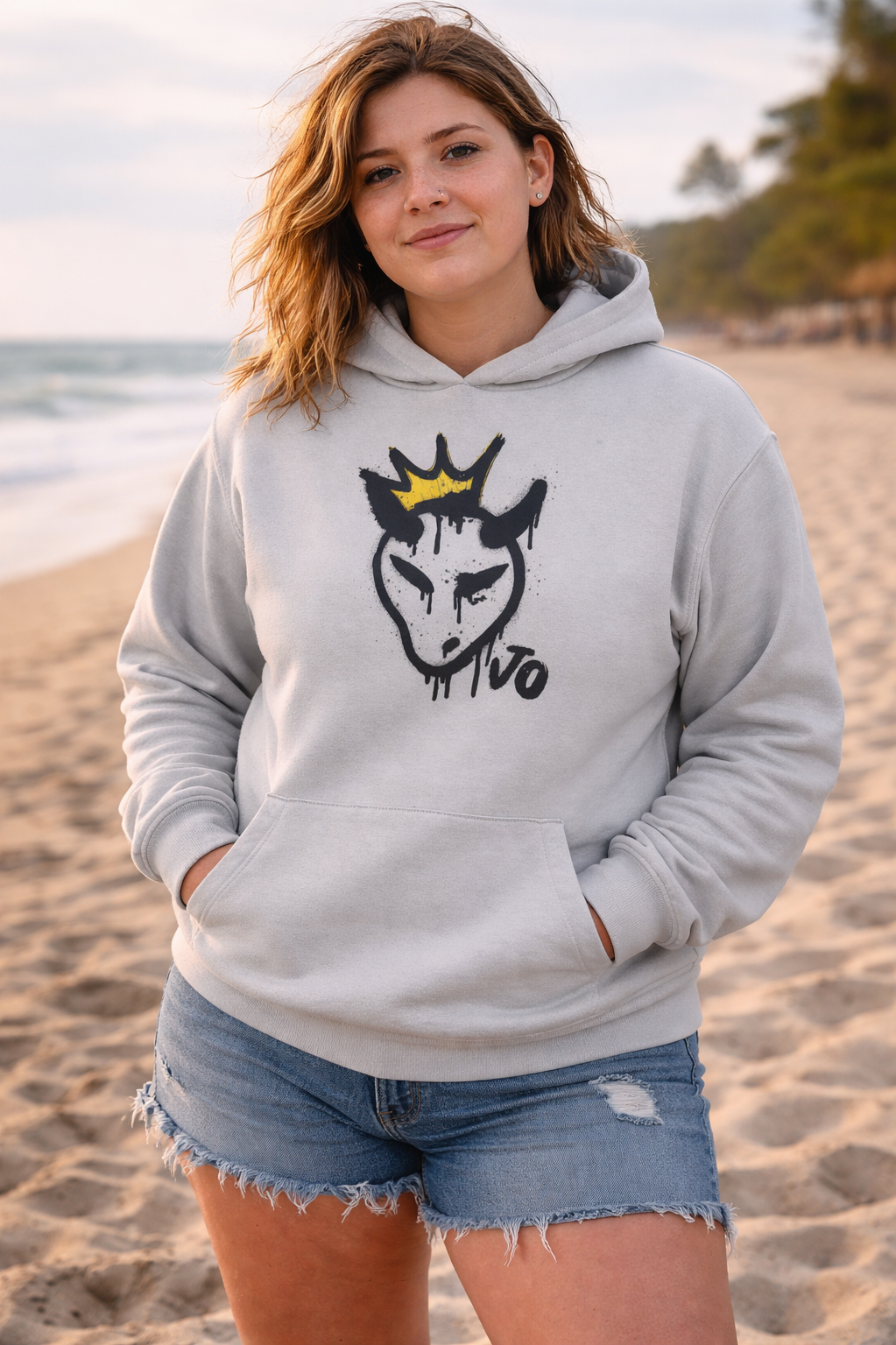 Person wearing a gray hoodie with a graphic design on a beach
