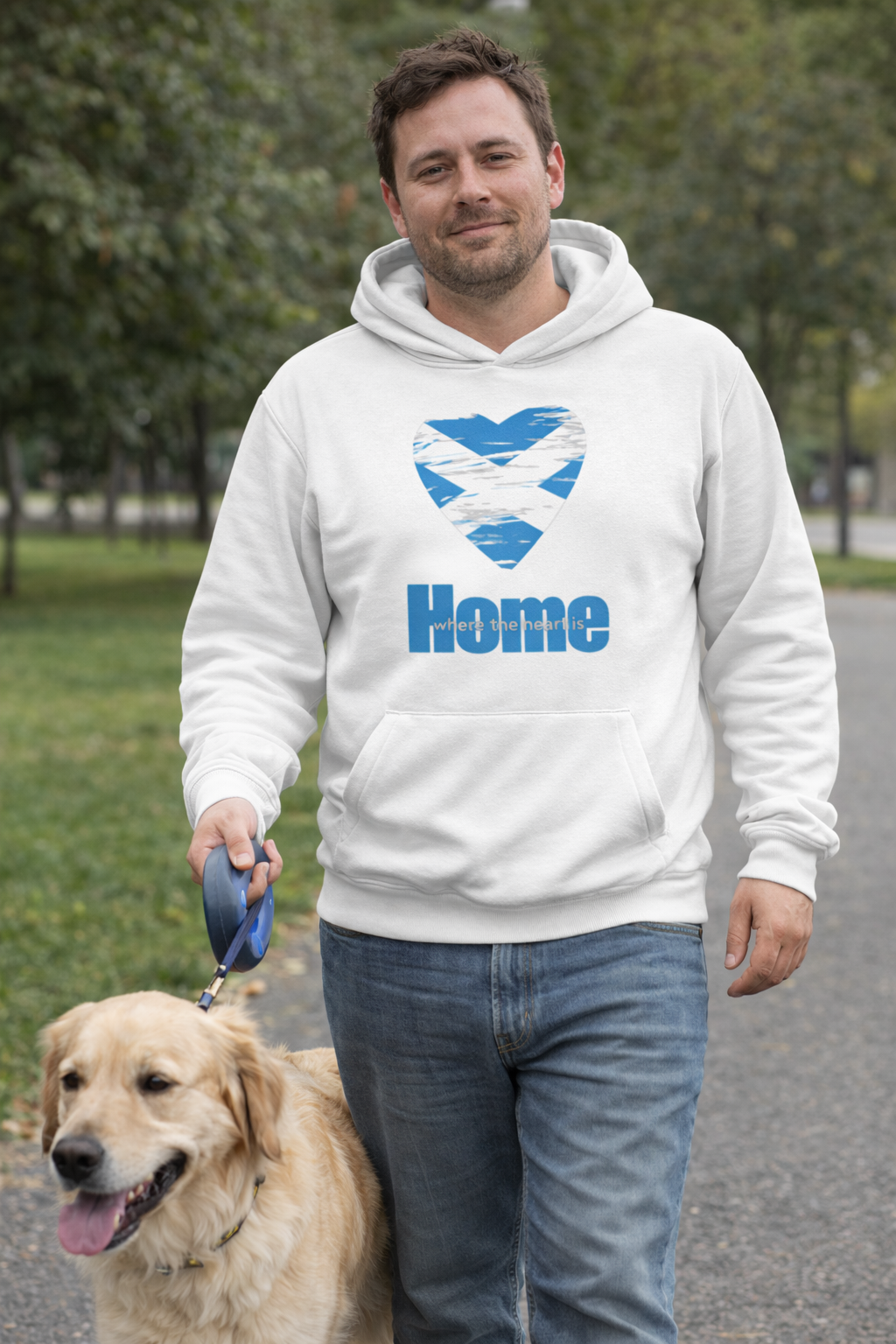 Man walking a dog wearing an arctic white hoodie with a saltire heart design and 'Home' text.